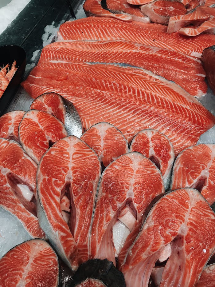 Close-up of fresh salmon fillets and steaks on ice, perfect for culinary presentations.