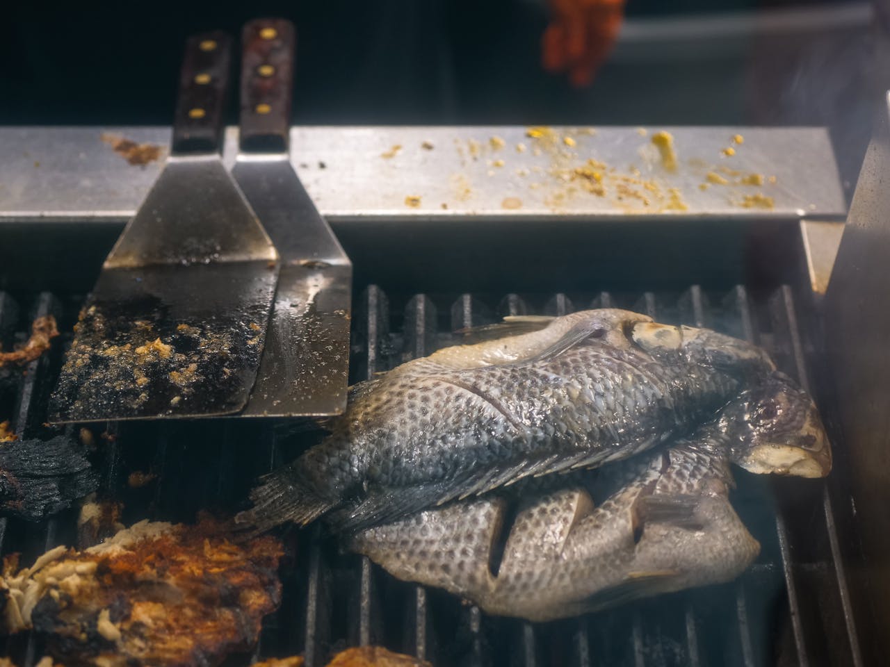 services-img A whole tilapia fish grilling on an outdoor barbecue, capturing a smoky and savory experience.