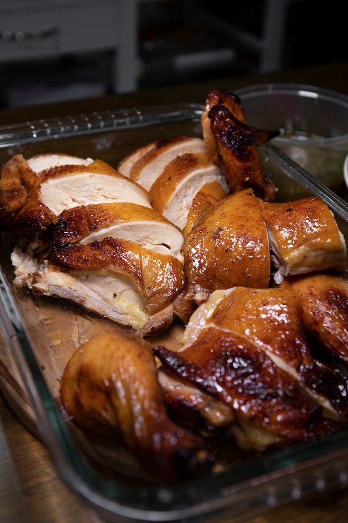 Succulent roasted chicken pieces displayed in a clear baking dish, deliciously golden and ready to serve.